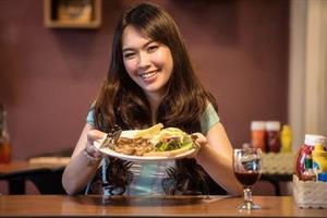 Woman showing steak dinner with wine