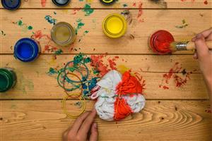 T-shirt wrapped in rubbed bands being painted in a tie-dye style.