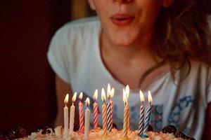 Girl blowing out candles on a birthday cake.