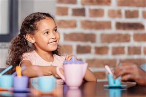 Little girl playing with a plastic tea set.